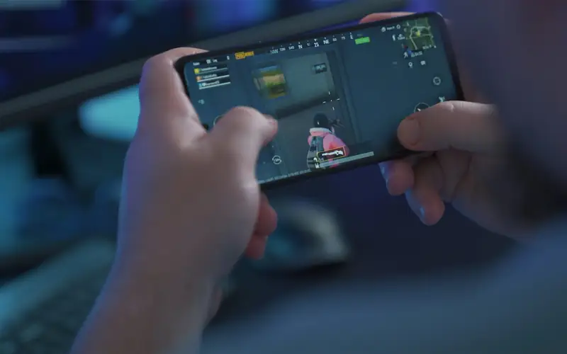 Close-up of two hands holding a phone in landscape mode during fast mobile gameplay